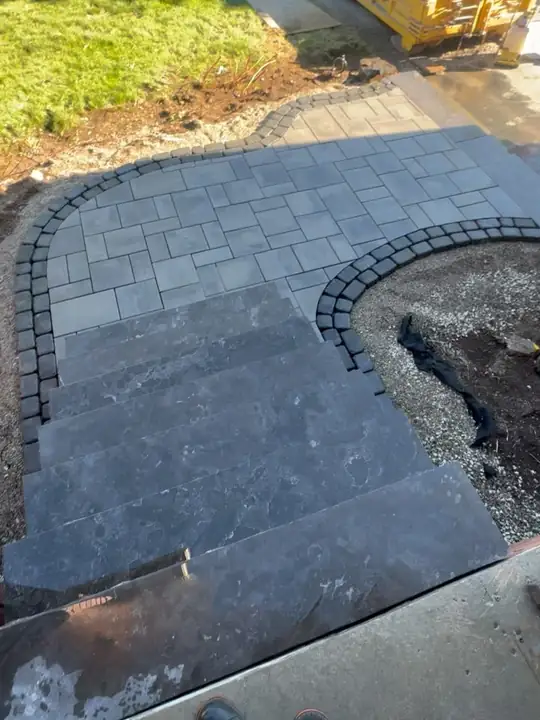 Curved paver walkway with a charcoal soldier course being installed